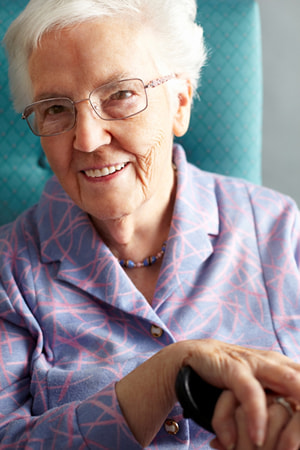 An older woman smiling sitting on a chair